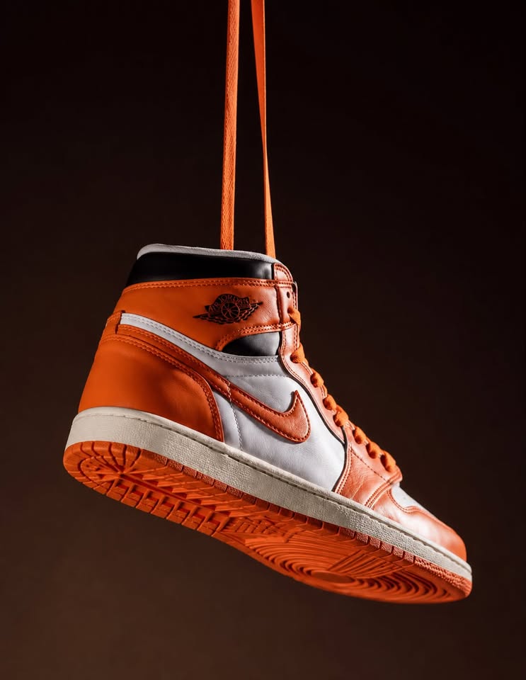 Orange, white and black Air Jordan 1 trainer hanging by its laces